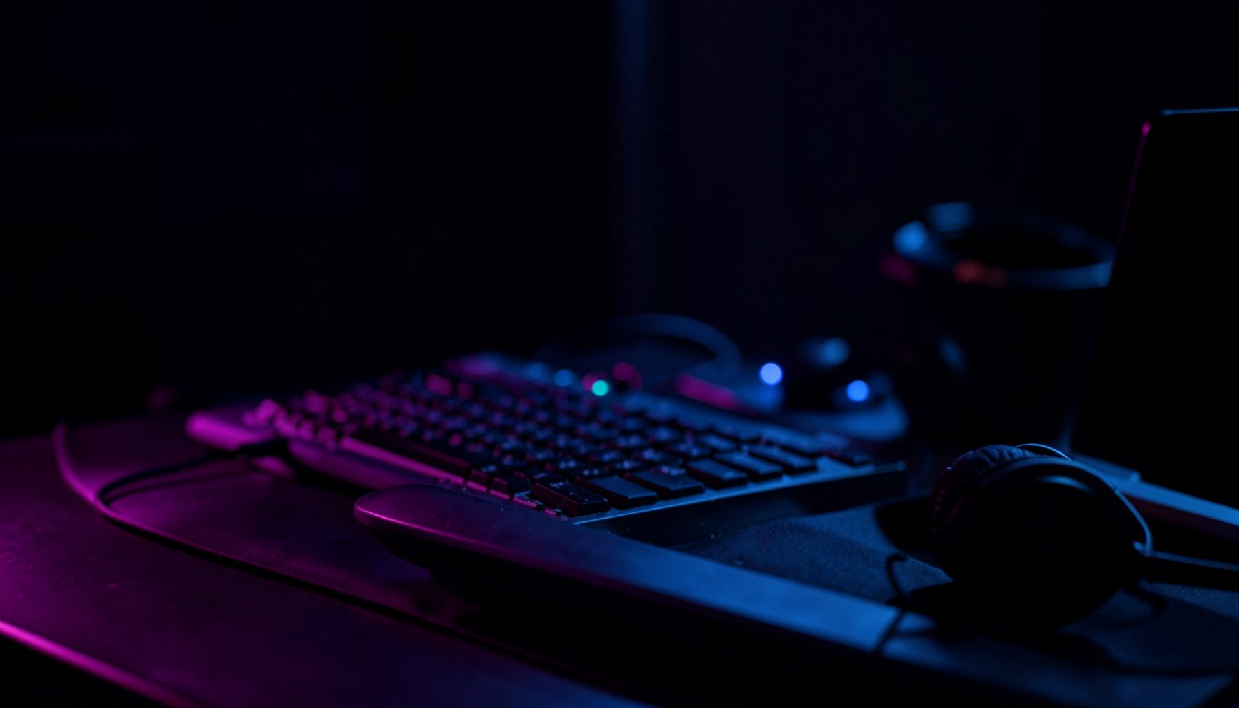 Ambiente escuro com iluminação roxa e azul, teclado e fones de ouvido sobre uma mesa, atmosfera de estúdio musical