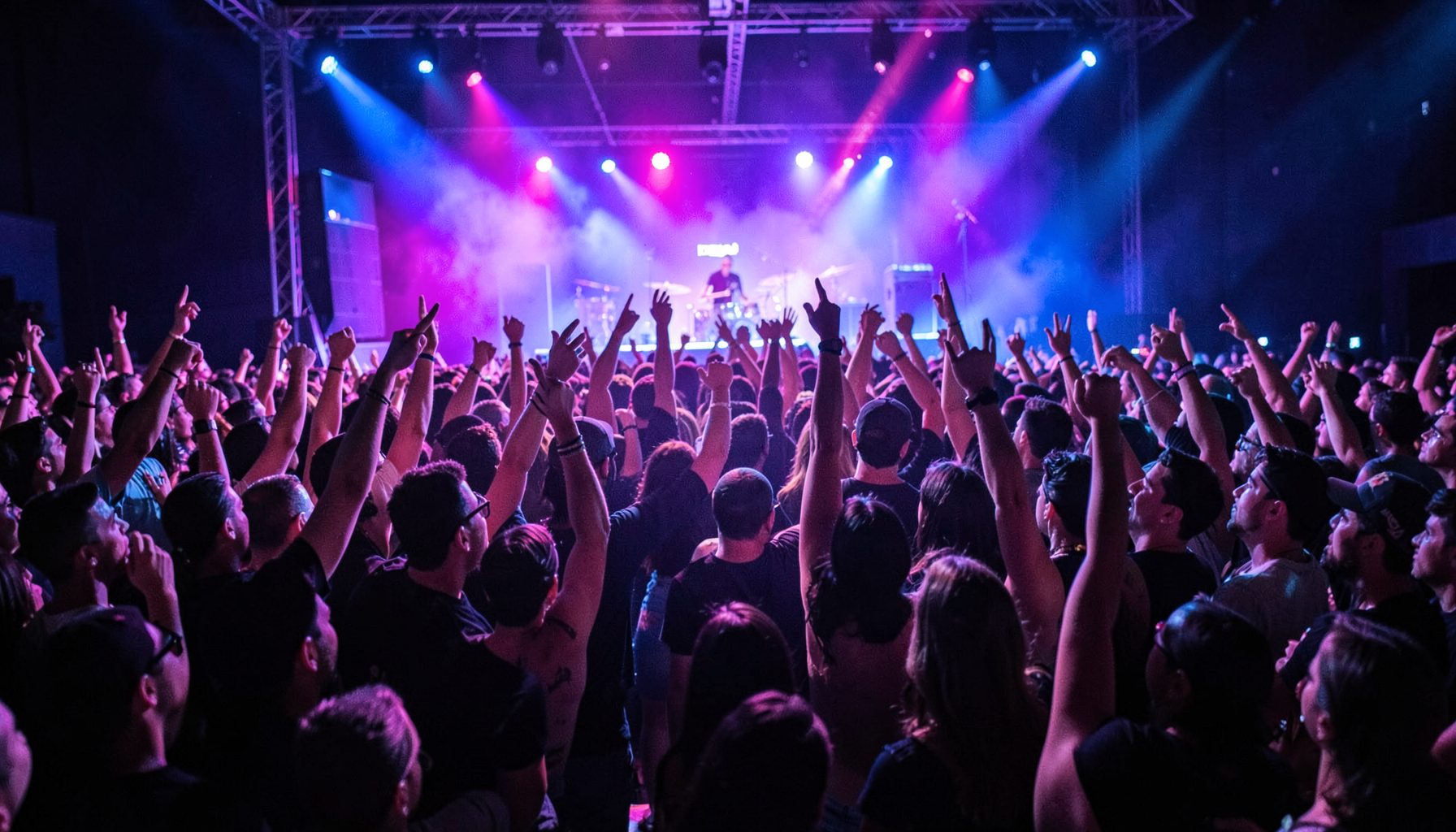 Multidão em show de rap com luzes roxas e azuis, mãos levantadas, clima de celebração e energia coletiva